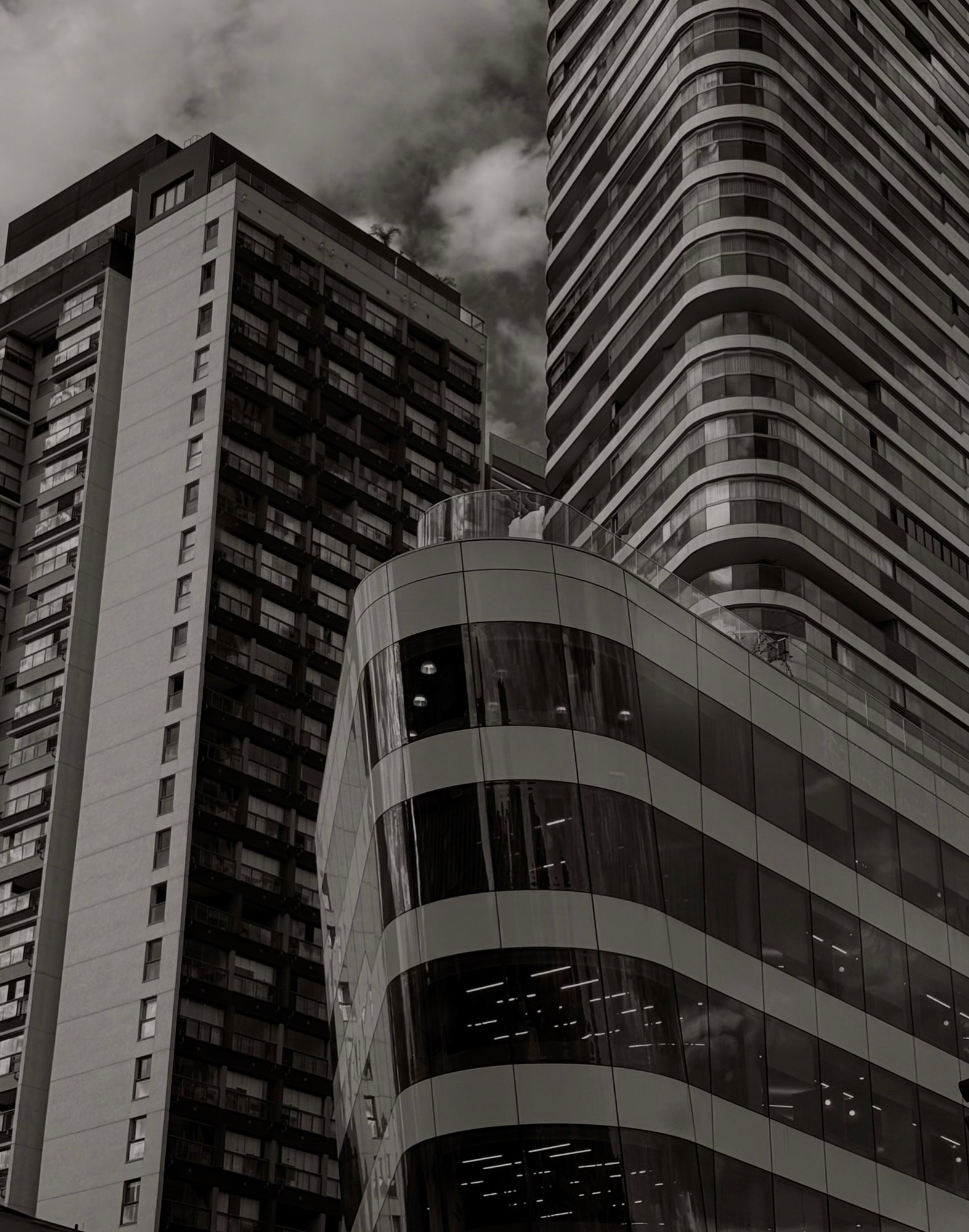 Curved glass building between towers, black and white
